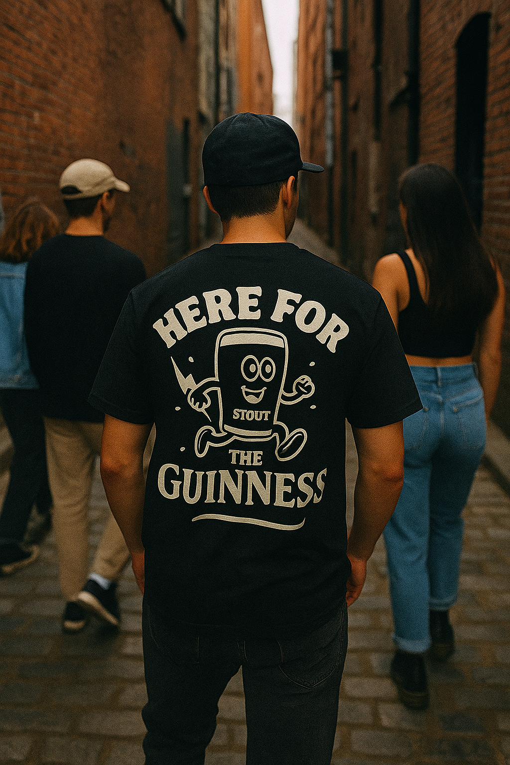 Person wearing 'Here for the Guinness' stout tee, strolling with friends in a vintage-style urban setting.