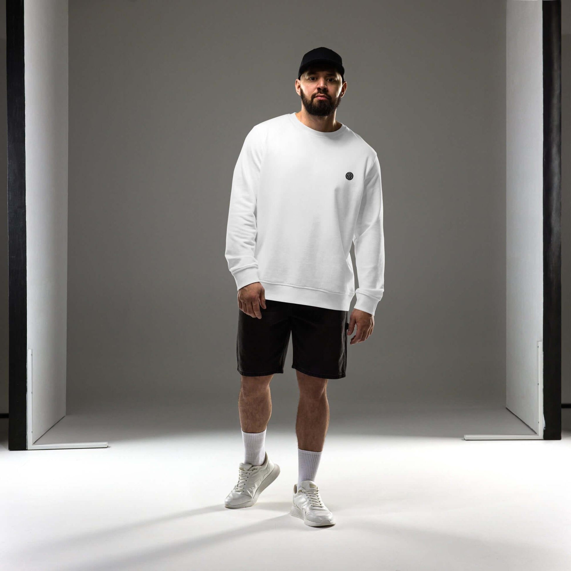 Man wearing a white sweatshirt and shorts, showcasing the Creamy Beamy Organic Sweatshirt's vintage design.