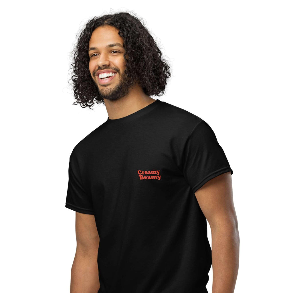 Smiling man in a black Creamy Beamy Tee, perfect for stout lovers and pub vibes, showcasing playful style.