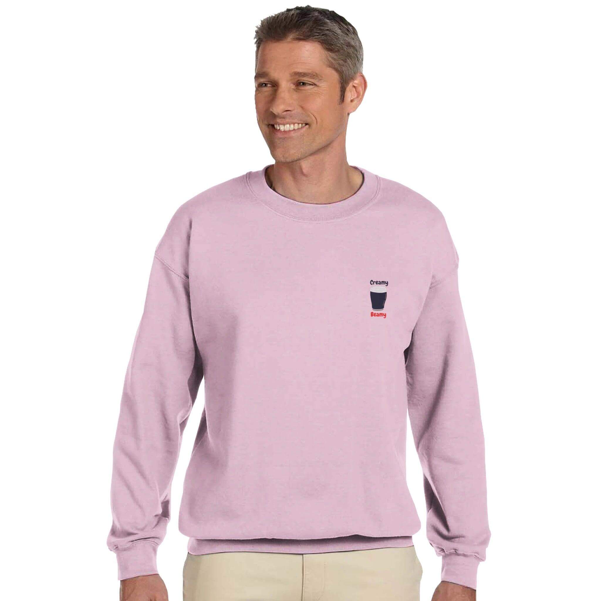 Man wearing a pink Creamy Beamy's Jumper sweatshirt, showcasing stylish design for Beamish Stout lovers.